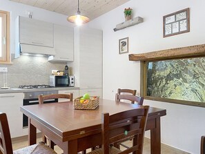 Eine moderne Küche mit weißen Schränken, einem Gasherd, einer Mikrowelle und einem Essbereich mit Holztisch und Stühlen.