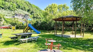 Ein Spielplatz mit Rutsche, Schaukeln und einem Picknicktisch.
