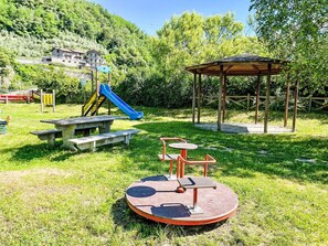 Ein Spielplatz mit Rutsche, Schaukeln und einem Picknicktisch.