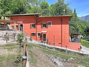 Un bâtiment rouge doté de nombreuses fenêtres, d’un balcon et d’un escalier en pierre.