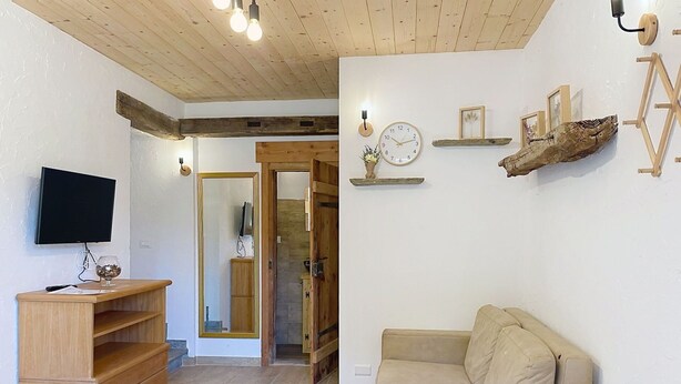Ein Wohnzimmer mit einem HolztV-Schrank, einem beigen Sofa, einer Holzzielung und einer an der Wand befestigten Uhr.