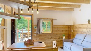 Un interior de madera con un sofá, una mesa con una cesta, un control remoto y una ventana con cortinas.