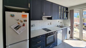 Uma cozinha moderna com armários escuros, uma geladeira branca, forno embutido e lava-louças.