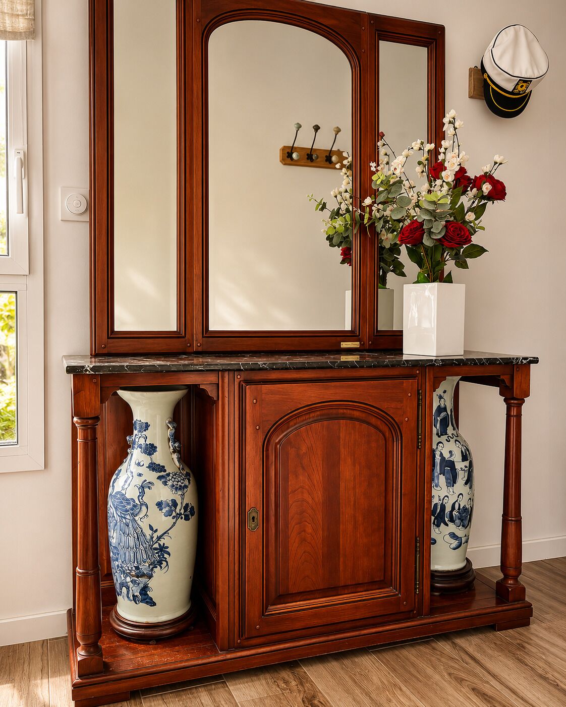 A wooden console table with a mirror, two vases, and a wall-mounted hat.