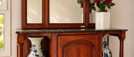 A wooden console table with a mirror, two vases, and a wall-mounted hat.