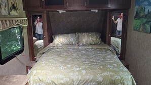 A bedroom with a bed, a television, and a door leading to another room.