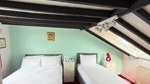 A bedroom with two beds, a red carpet, a white radiator, and a skylight. - Fjaerland Hotel (Great Yarmouth)