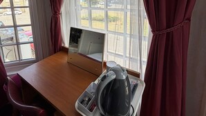 A room with a wooden desk, a mirror, a kettle, and a window with curtains. - Fjaerland Hotel (Great Yarmouth)