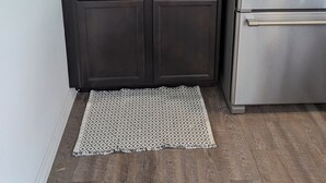 Una cocina con armarios oscuros, un refrigerador de acero inoxidable, una cafetera, un dispensador de agua y una planta pequeña en la encimera.