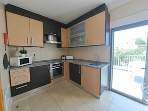 A modern kitchen with a microwave, toaster, oven, and a large window. - Apartment SEA & OLD TOWN VIEWS (Albufeira)