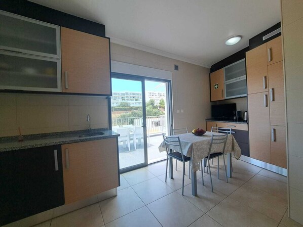 A modern kitchen with a dining area, large windows, and a view of buildings. - Apartment SEA & OLD TOWN VIEWS (Albufeira)