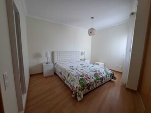 A bedroom with a bed, two bedside tables, a hanging light fixture, and a wooden floor. - Apartment SEA & OLD TOWN VIEWS (Albufeira)