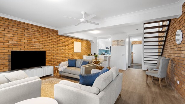 Ein modernes Wohnzimmer mit Backsteinwand, Flachbildfernseher und Deckenventilator.