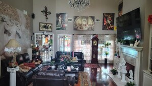 Un salón amplio con chimenea, sofás de cuero, una araña y diversas obras de arte.
