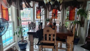 Un comedor con una mesa y sillas de madera, plantas en macetas y una araña.