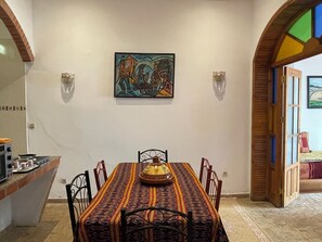 A dining area with a patterned tablecloth, a central decorative item, and a painting on the wall.