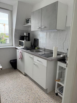 A compact kitchen with a microwave, coffee maker, and a small sink. - 2-room apartment on the North Sea directly on the dyke (Cuxhaven)