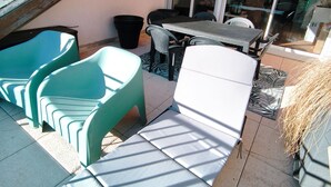 Una terrazza all'aperto con tavolo, sedie e un'area coperta.