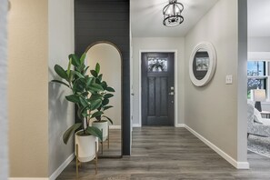 A hallway with a potted plant, a door with a glass panel, and a light fixture. - LUXURY COUNTRY RETREAT ~ PICKLEBALL COURT, FIRE PIT & COUNTRY VIEWS (Wauseon)