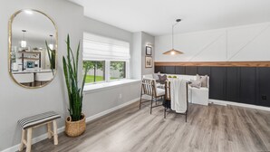 Uma sala de estar moderna com área de refeições, um espelho grande e vista para o exterior.