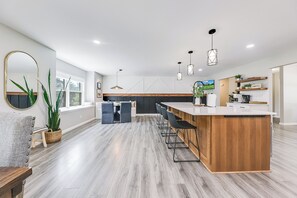 Una cocina moderna con una isla central, asientos tipo bar e iluminación colgante.