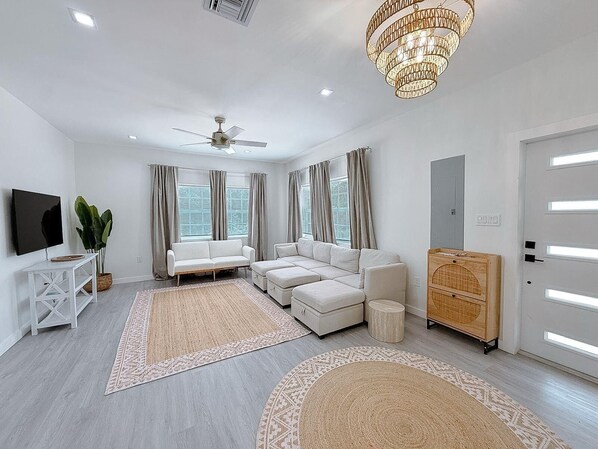 Ein modernes Wohnzimmer mit Deckenventilator, einer großen Kronleuchter und einer Sofagarnitur.