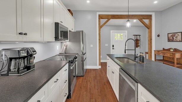 Una cocina moderna con armarios blancos, electrodomésticos de acero inoxidable y suelo de madera.