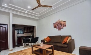 A living room with a sofa, coffee table, and a ceiling fan. - 2-bedroom apartment in serene Adenta Municipality with AC (Adenta Municipality)