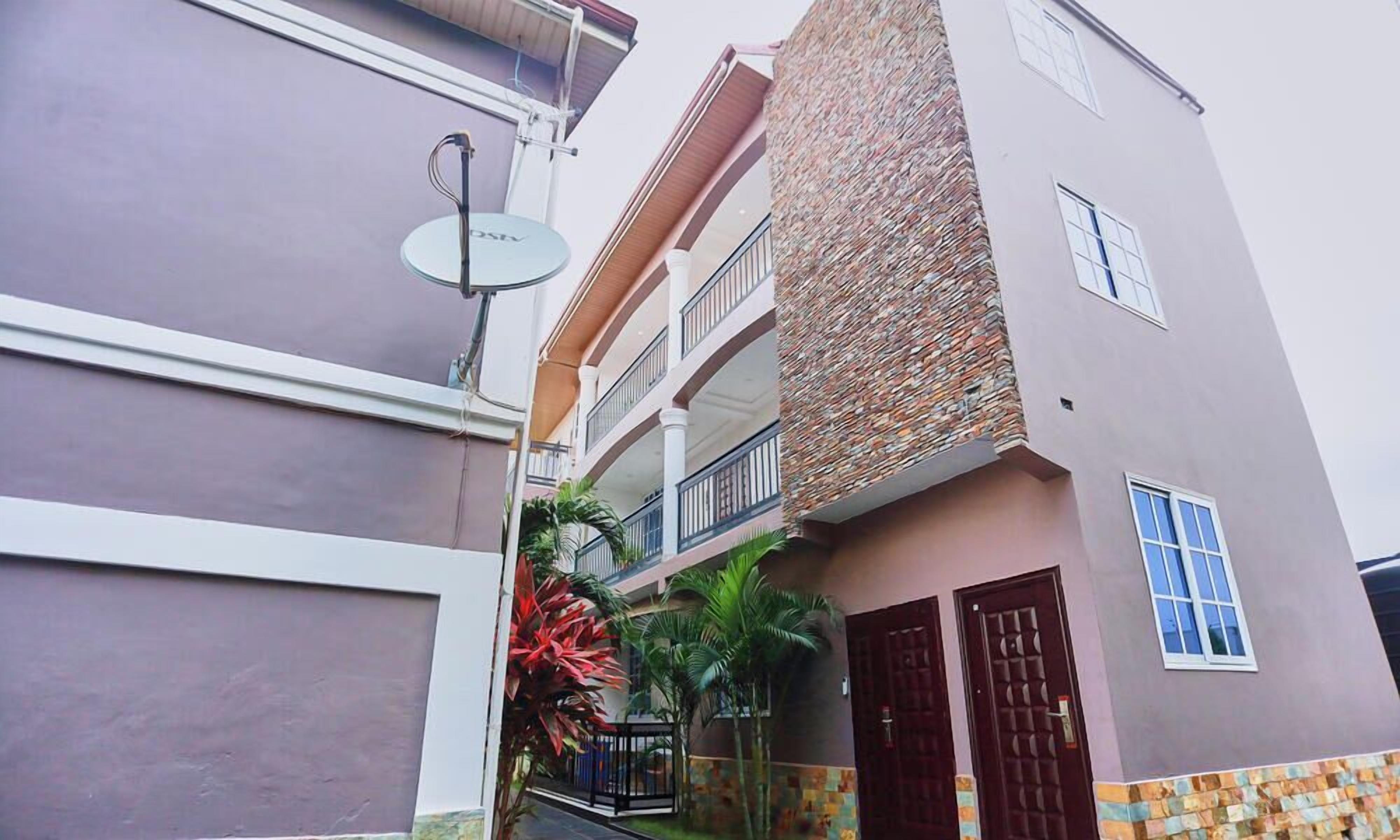 A multi-story building with balconies, a satellite dish, and a gated entrance.