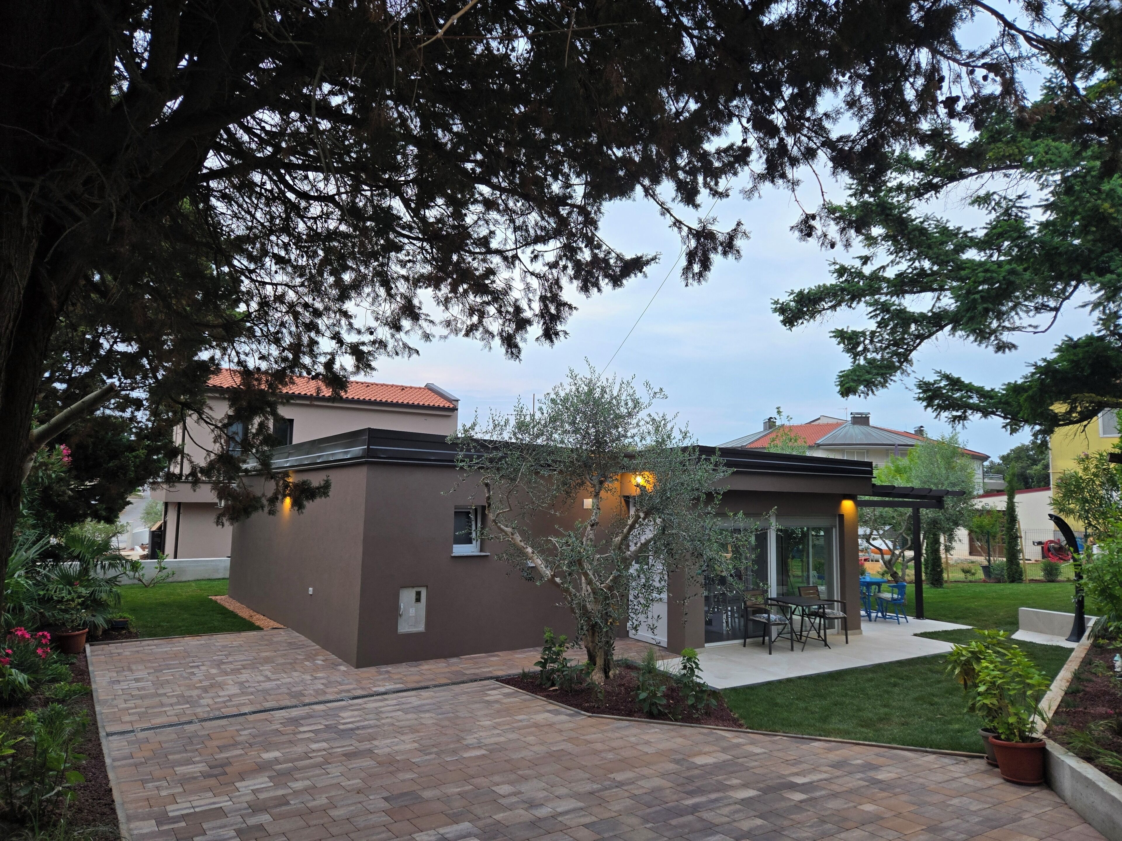 A modern house with a patio, a small garden, and a dining area.