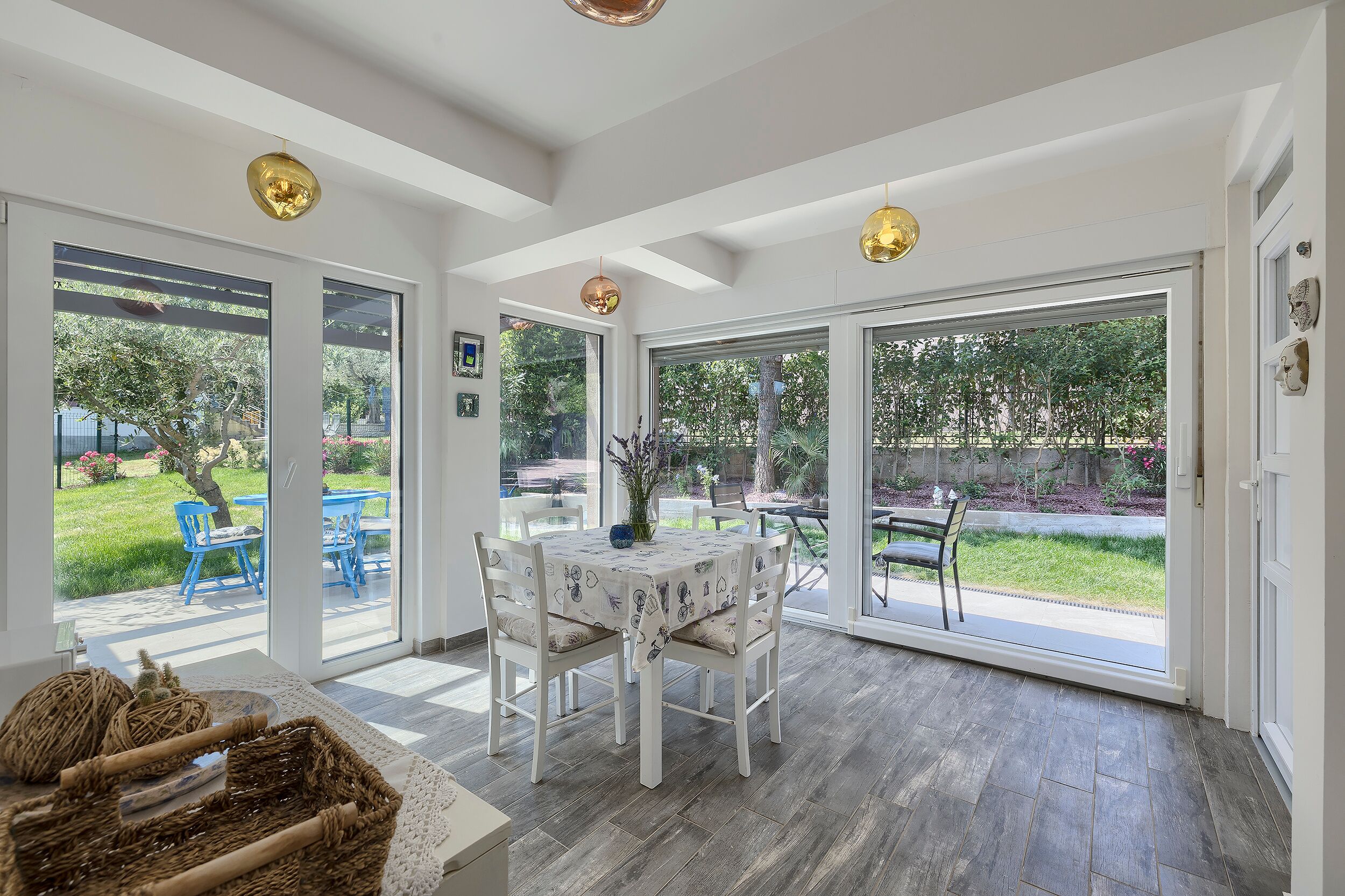 A dining area with a table and chairs, large sliding glass doors leading to an outdoor patio, and a ceiling with pendant lights.