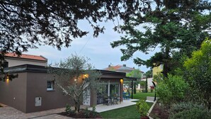 A courtyard with a patio area, a covered seating area, and a building with a brown exterior. - Mediterranean oasis of peace- 100 m from the sea, private garden ful fenced yard (Banjole)