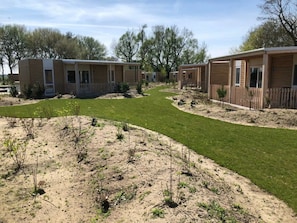 A row of mobile homes with a grassy pathway between them. - Cosy Unique 2+4 (Nunspeet)