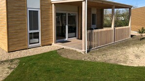 Ein modernes Gebäude mit einer überdachten Terrasse, großen Schiebeglastüren und einem Holzzaun.