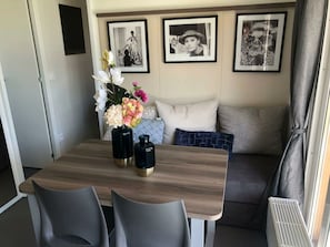 A dining area with a wooden table, two black vases with gold accents, and a floral arrangement. - Cosy Unique 2+4 (Nunspeet)