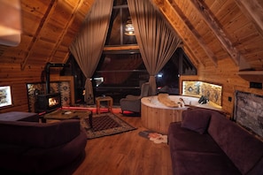 Interior acogedor de una cabaña de troncos con chimenea, un jacuzzi y una zona de estar confortable.
