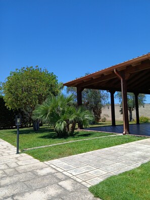 A covered outdoor area with a tiled walkway, a palm tree, and a lamp post. - 2-bedroom apartment in villa! (San Donato Di Lecce)