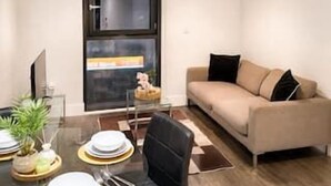 Un salon moderne avec une table à manger en verre, un canapé et un téléviseur.