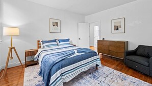 A bedroom with a bed, bedside tables, a dresser, a lamp, and framed pictures on the walls. - Large home on a quiet street close to attractions (Baltimore)