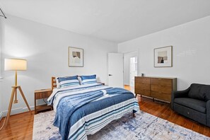 A bedroom with a bed, bedside tables, a dresser, a lamp, and framed pictures on the walls. - Large home on a quiet street close to attractions (Baltimore)