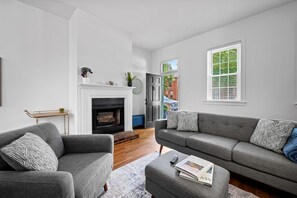 Ein Wohnzimmer mit Kamin, grauen Sofas und einem Couchtisch.