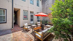 A patio area with outdoor furniture, a red umbrella, and a brick floor. - Large home on a quiet street close to attractions (Baltimore)