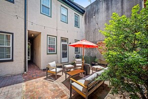 A patio area with outdoor furniture, a red umbrella, and a brick floor. - Large home on a quiet street close to attractions (Baltimore)
