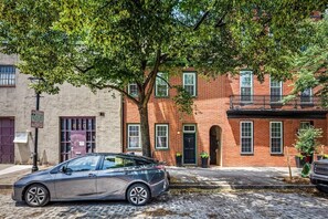 A two-story brick building with a car parked on the street in front. - Large home on a quiet street close to attractions (Baltimore)