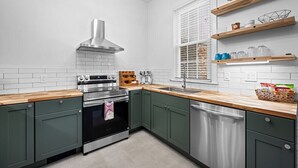 A modern kitchen with stainless steel appliances, green cabinets, and wooden countertops. - Large home on a quiet street close to attractions (Baltimore)