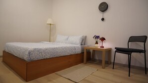 Une chambre à coucher avec un lit, une table de chevet, une lampe, une chaise et une horloge murale.