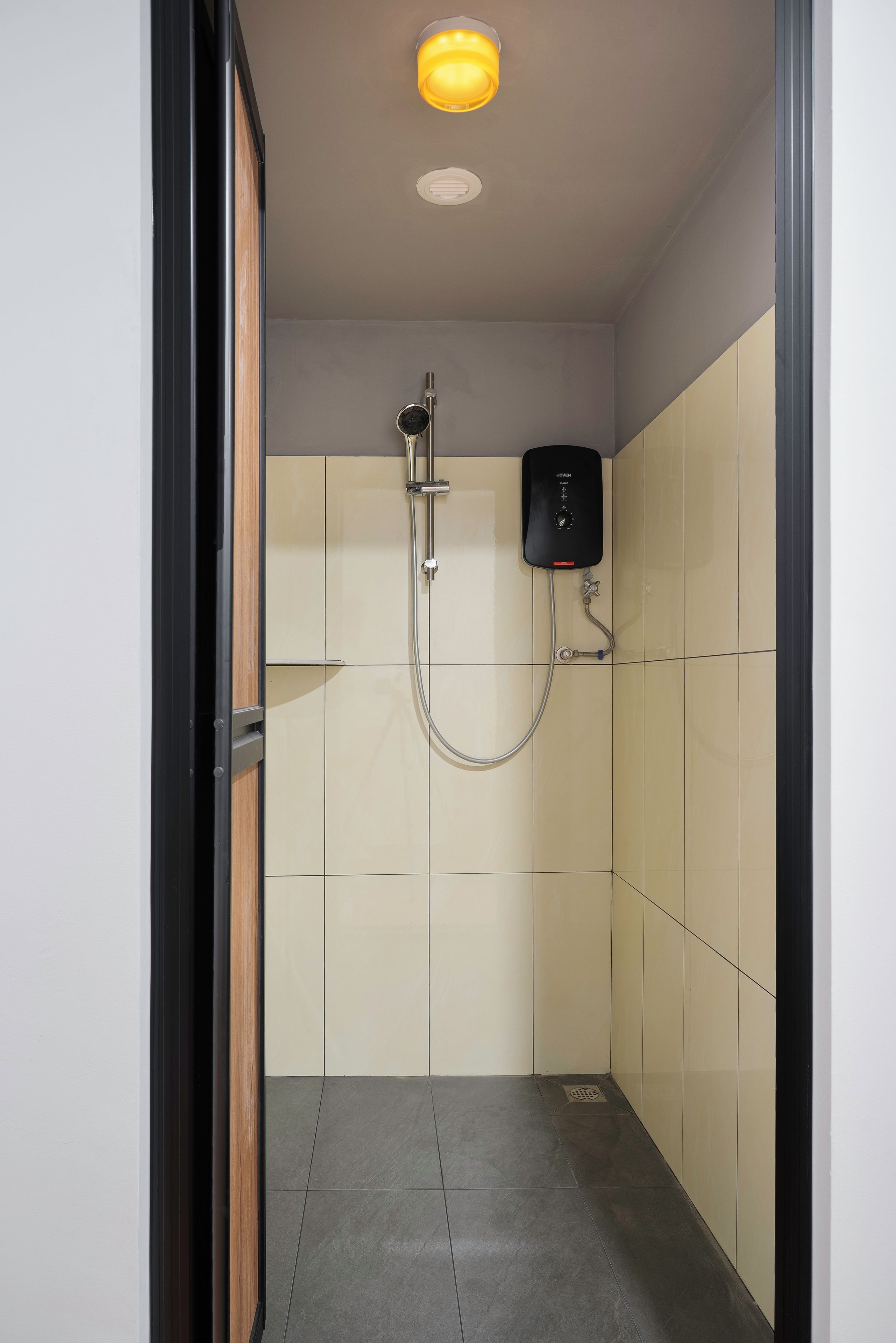 Um chuveiro fechado e pequeno, com um chuveiro manual, painel de controle e piso revestido de azulejos.