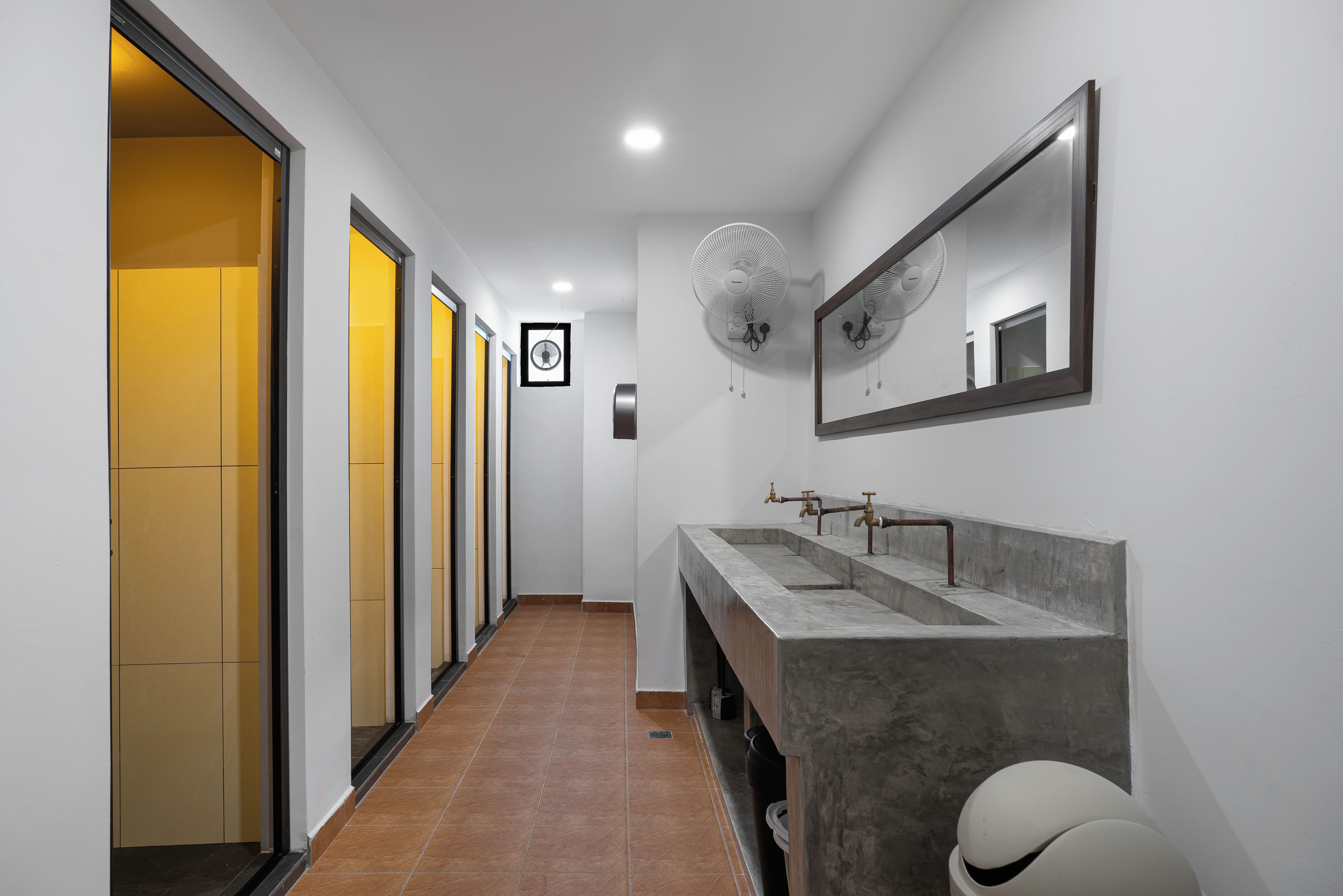 Un baño moderno con un tocador espacioso, un espejo grande y un ventilador de pared.