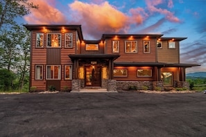 A two-story log cabin with a stone foundation, multiple windows, and a number '997' on the front door. - Indoor Pool | Golf Sim | Pickleball | Sleeps 20 (Sevierville)