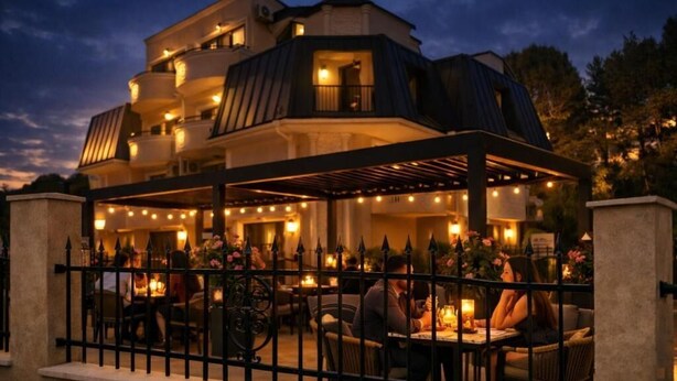 A multi-story building with outdoor seating and a covered patio area. - Raya Boutique (Sunny Beach)